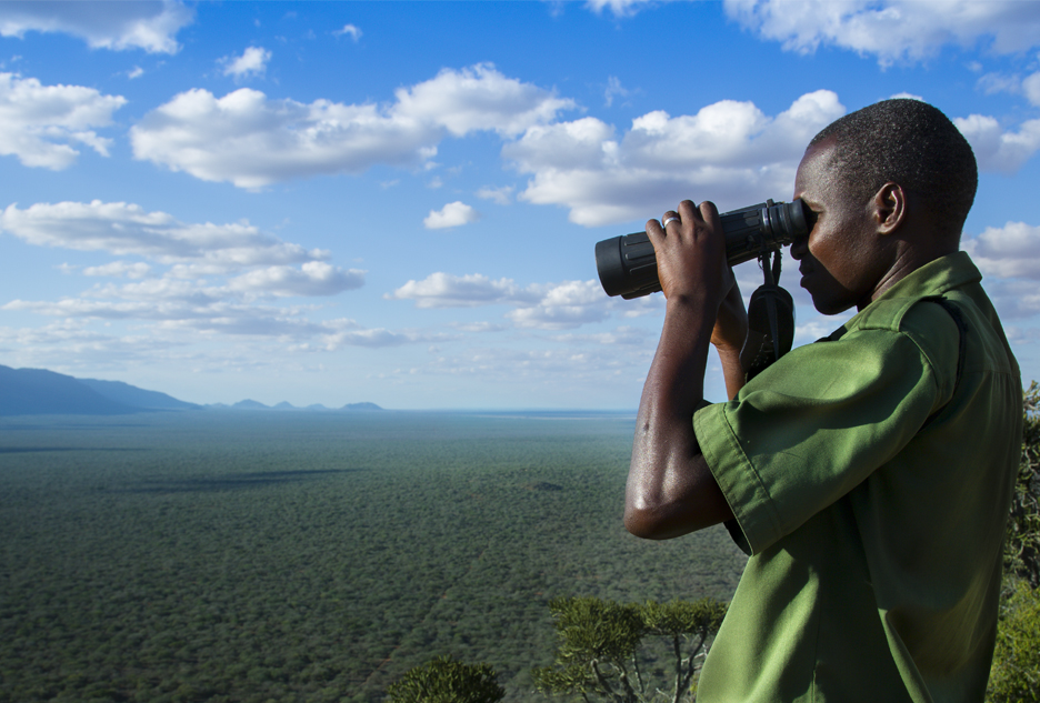 person uses binoculars to look over Kasigau